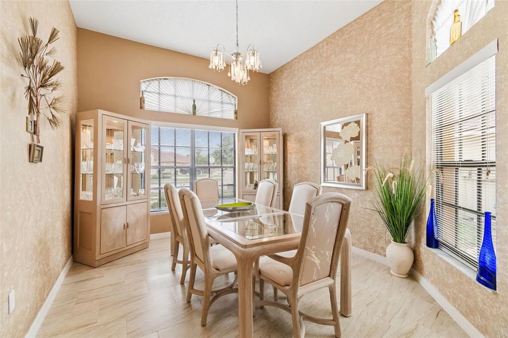 A dining room with a glass-top table, six chairs, two china cabinets, and textured walls — 9311 HAAS DRIVE, HUDSON, FL