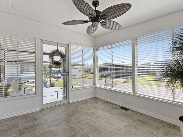 A sunroom features tile flooring, a ceiling fan, and large windows with white blinds — 1401 W HIGHWAY 50 UNIT 45, CLERMONT, FL