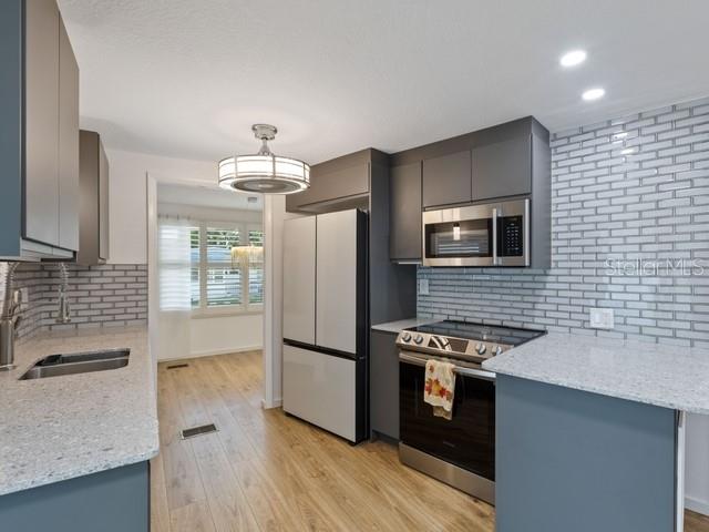 A modern kitchen features gray cabinets, stainless steel appliances, and a light-colored granite countertop — 1401 W HIGHWAY 50 UNIT 45, CLERMONT, FL