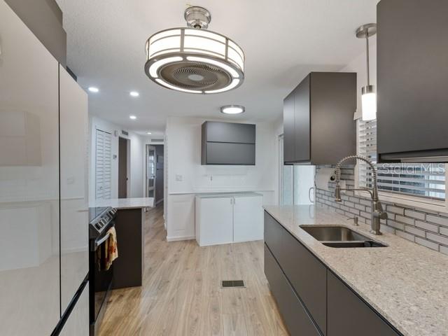 A modern kitchen features dark cabinetry, light countertops, a ceiling fan, and light wood flooring — 1401 W HIGHWAY 50 UNIT 45, CLERMONT, FL