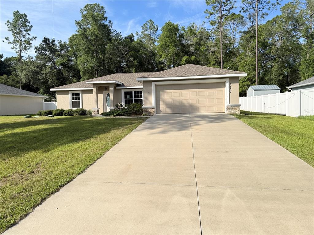 A single-story house with a beige exterior, a two-car garage, and a concrete driveway — 9850 N SANDREE DRIVE, CITRUS SPRINGS, FL