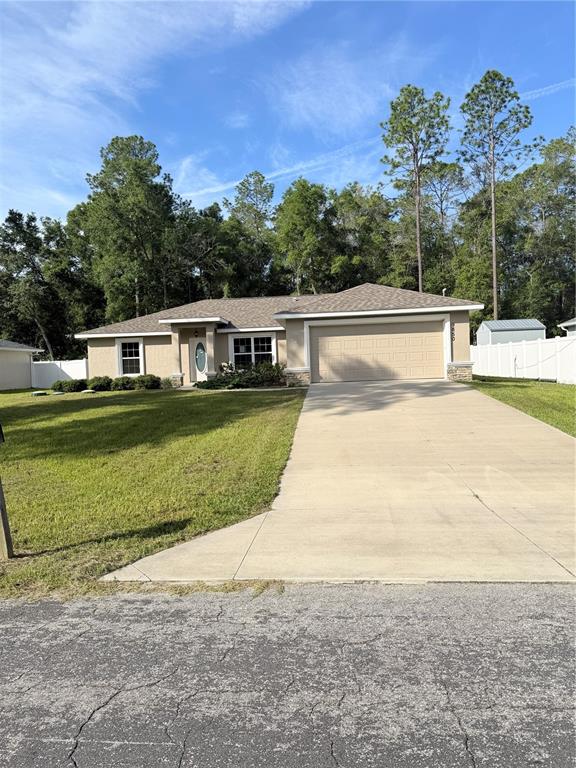 A single-story house with a beige exterior, a two-car garage, and a concrete driveway — 9850 N SANDREE DRIVE, CITRUS SPRINGS, FL