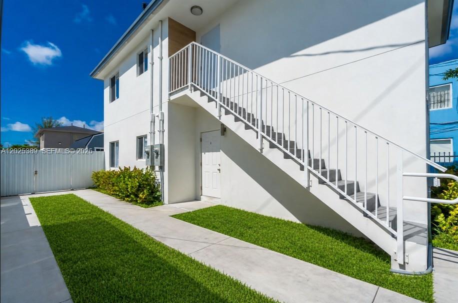 A two-story white building features an exterior staircase leading to an upper-level entrance — 1180 NW 67th St # 2, Miami FL 33150, MIAMI, FL