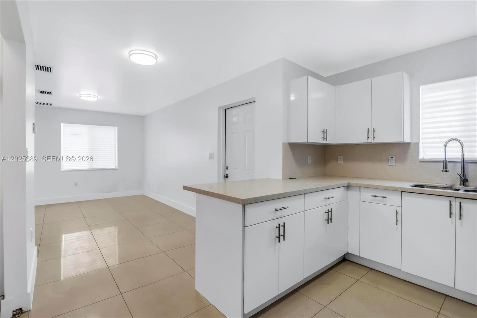 A kitchen with white cabinets and a peninsula overlooks an adjacent dining area — 1180 NW 67th St # 2, Miami FL 33150, MIAMI, FL