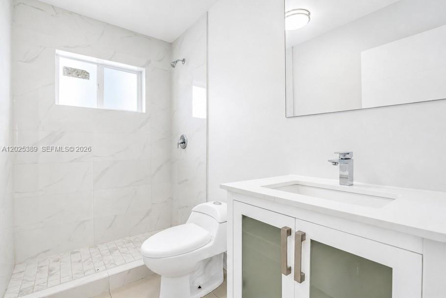 A modern bathroom features white marble-look wall tiles, a glass-enclosed shower, and a white vanity — 1180 NW 67th St # 2, Miami FL 33150, MIAMI, FL
