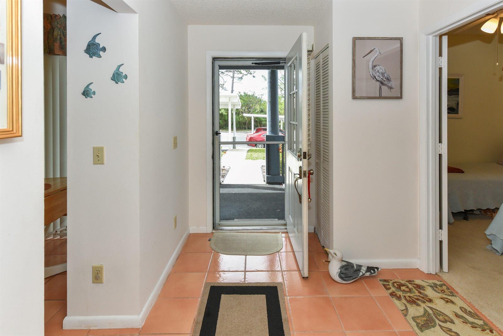 An entryway with terracotta tile floors features a front door opening to an outdoor walkway — 1637 NE Nautical Place # 802, Jensen Beach FL 34957, JENSEN BEACH, FL