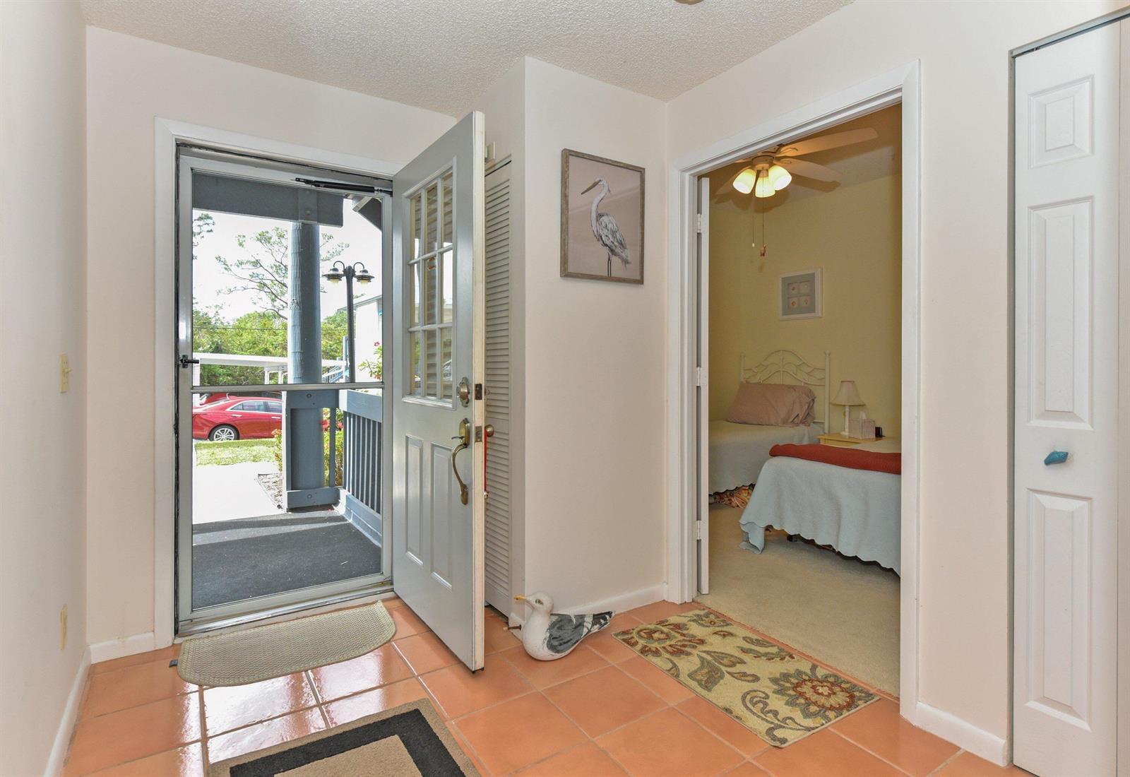 An entryway with orange tile flooring leads to an open door and a bedroom beyond — 1637 NE Nautical Place # 802, Jensen Beach FL 34957, JENSEN BEACH, FL