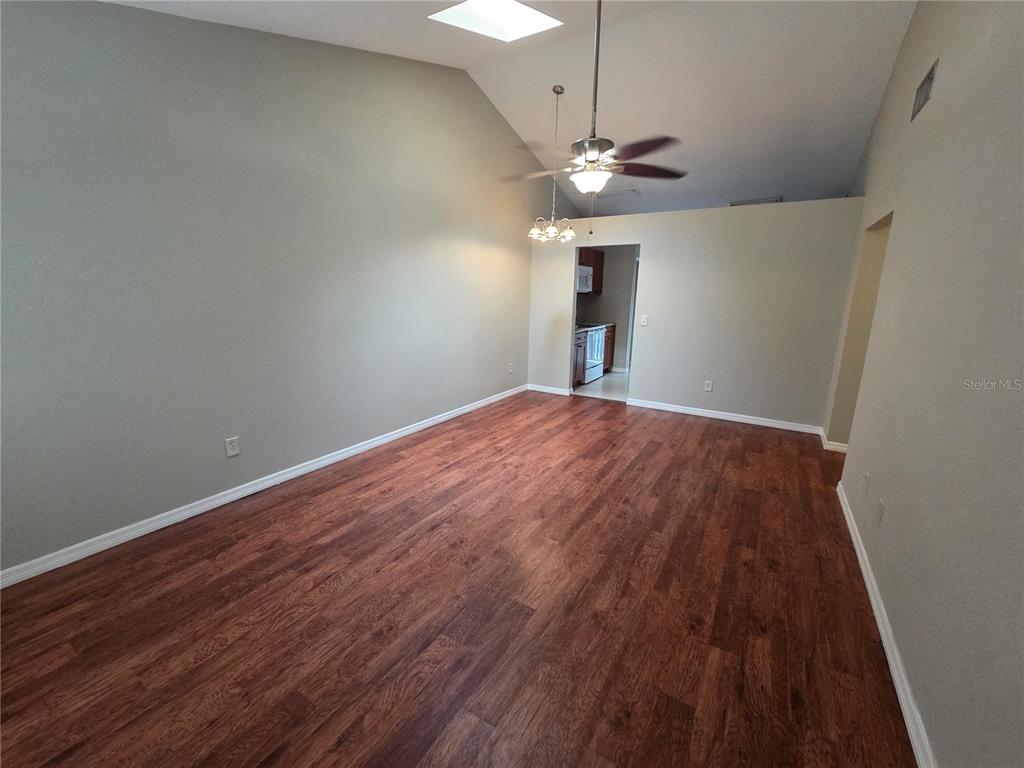 An empty living room features vaulted ceilings, a ceiling fan, and dark wood-look flooring — 320 ERON WAY UNIT 6, WINTER GARDEN, FL