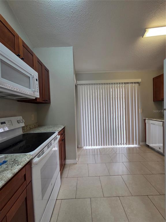 A kitchen with wood cabinets, white appliances, granite countertops, and tile flooring — 320 ERON WAY UNIT 6, WINTER GARDEN, FL