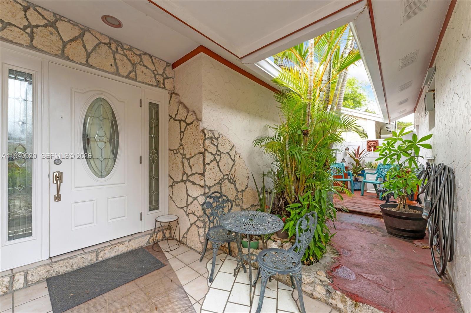 A white front door opens onto a tiled patio with a small bistro set — 1304 Redstart Ct, Homestead FL 33035, HOMESTEAD, FL