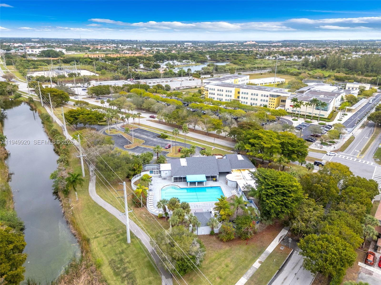 An aerial view shows a community swimming pool and clubhouse next to a canal — 1304 Redstart Ct, Homestead FL 33035, HOMESTEAD, FL