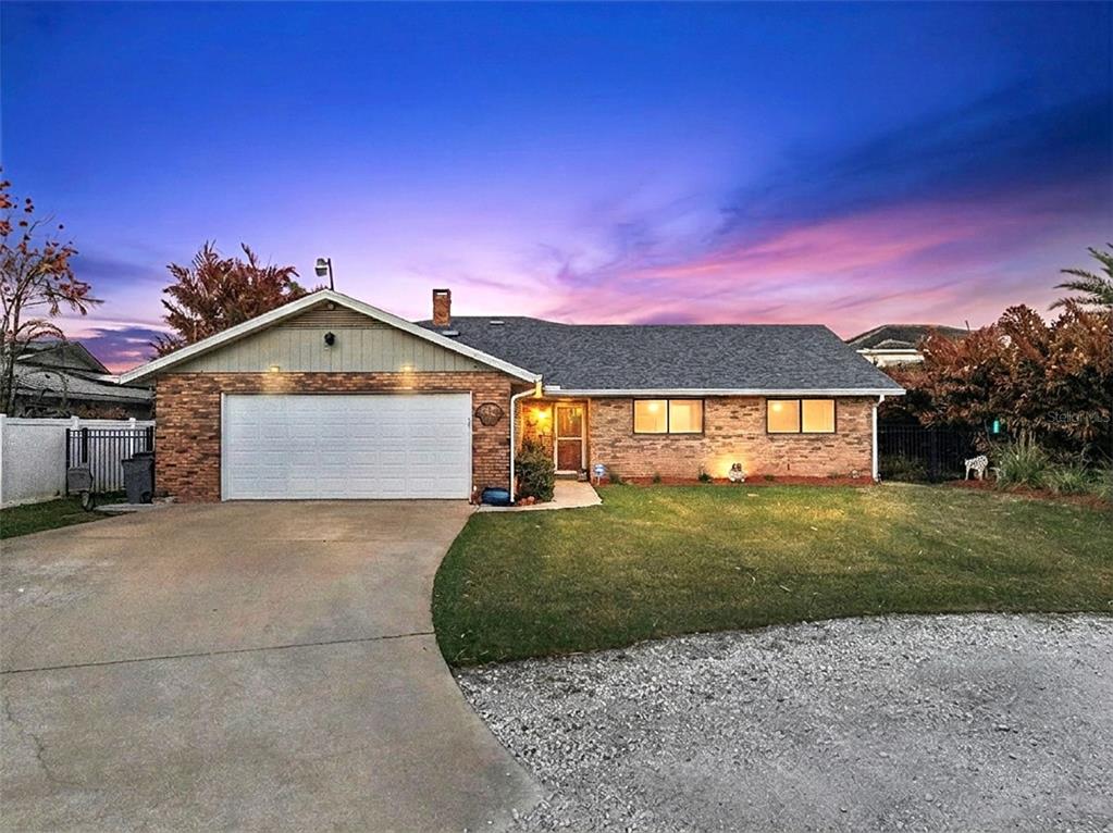 A single-story brick house features a two-car garage, a front lawn, and a gravel driveway — 1703 S RIVERSIDE DRIVE, NEW SMYRNA BEACH, FL