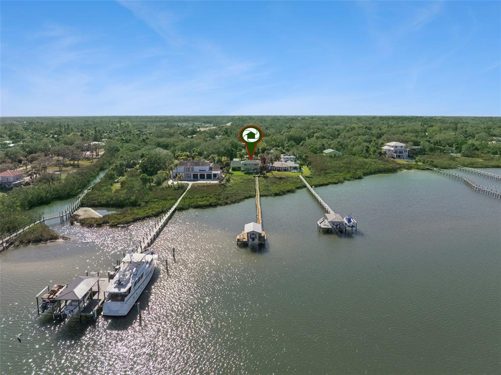 An aerial view shows a waterfront house with a long dock and boat lift — 1703 S RIVERSIDE DRIVE, NEW SMYRNA BEACH, FL
