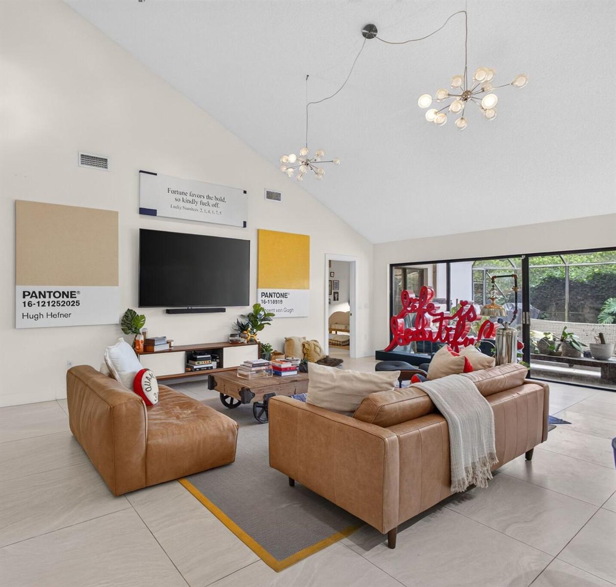 A modern living room features two tan leather sofas, a television, and large Pantone-themed wall art — 2613 Mohawk Circle, West Palm Beach FL 33409, WEST PALM BEACH, FL