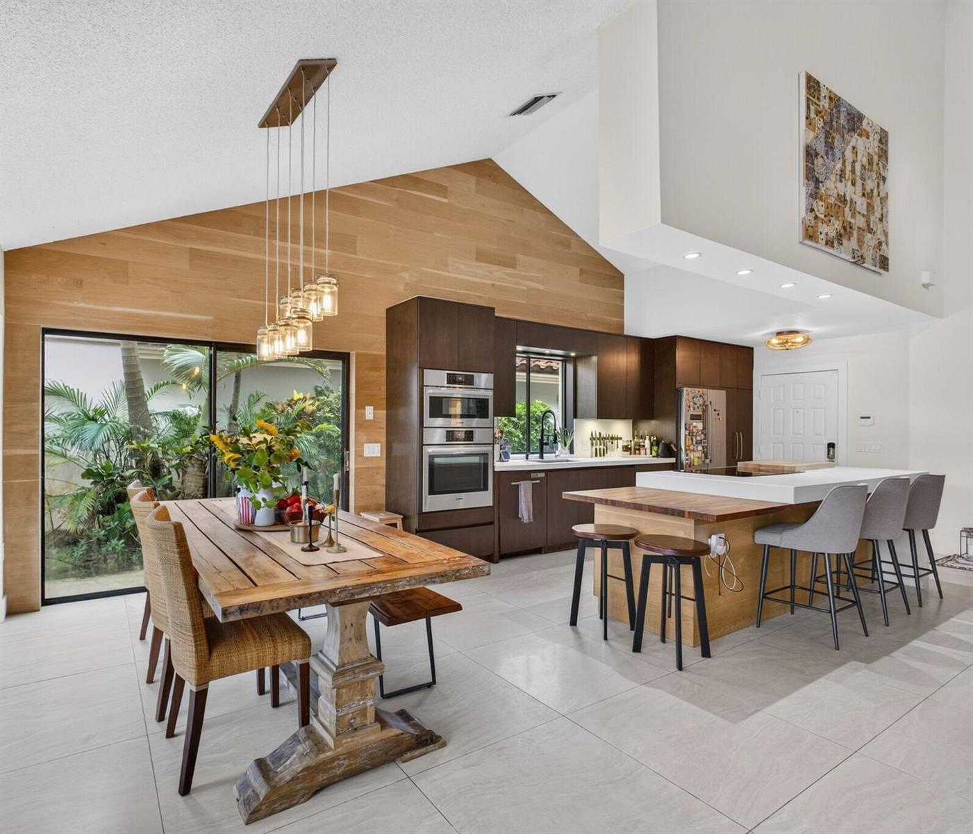 A modern kitchen and dining area feature wood-paneled vaulted ceilings and a large wooden table — 2613 Mohawk Circle, West Palm Beach FL 33409, WEST PALM BEACH, FL