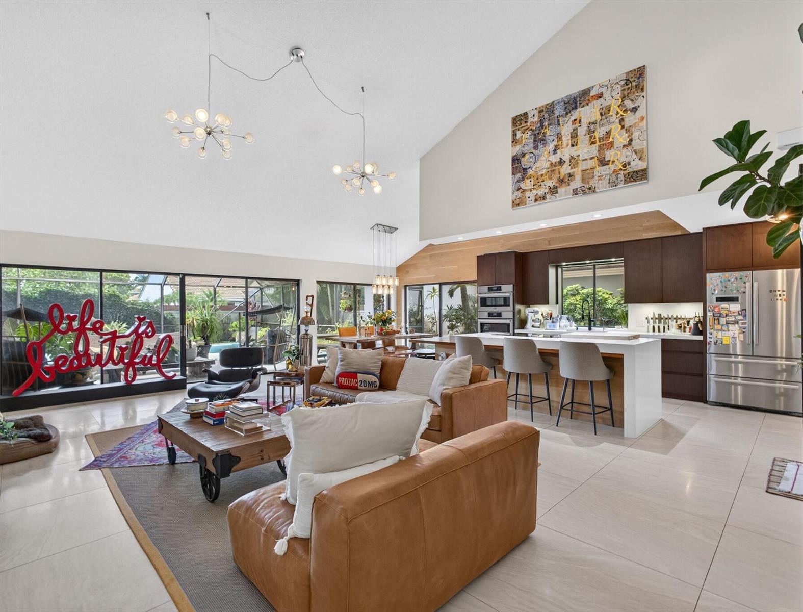 A spacious open-concept living room and kitchen with vaulted ceilings, tile floors, and leather sofas — 2613 Mohawk Circle, West Palm Beach FL 33409, WEST PALM BEACH, FL