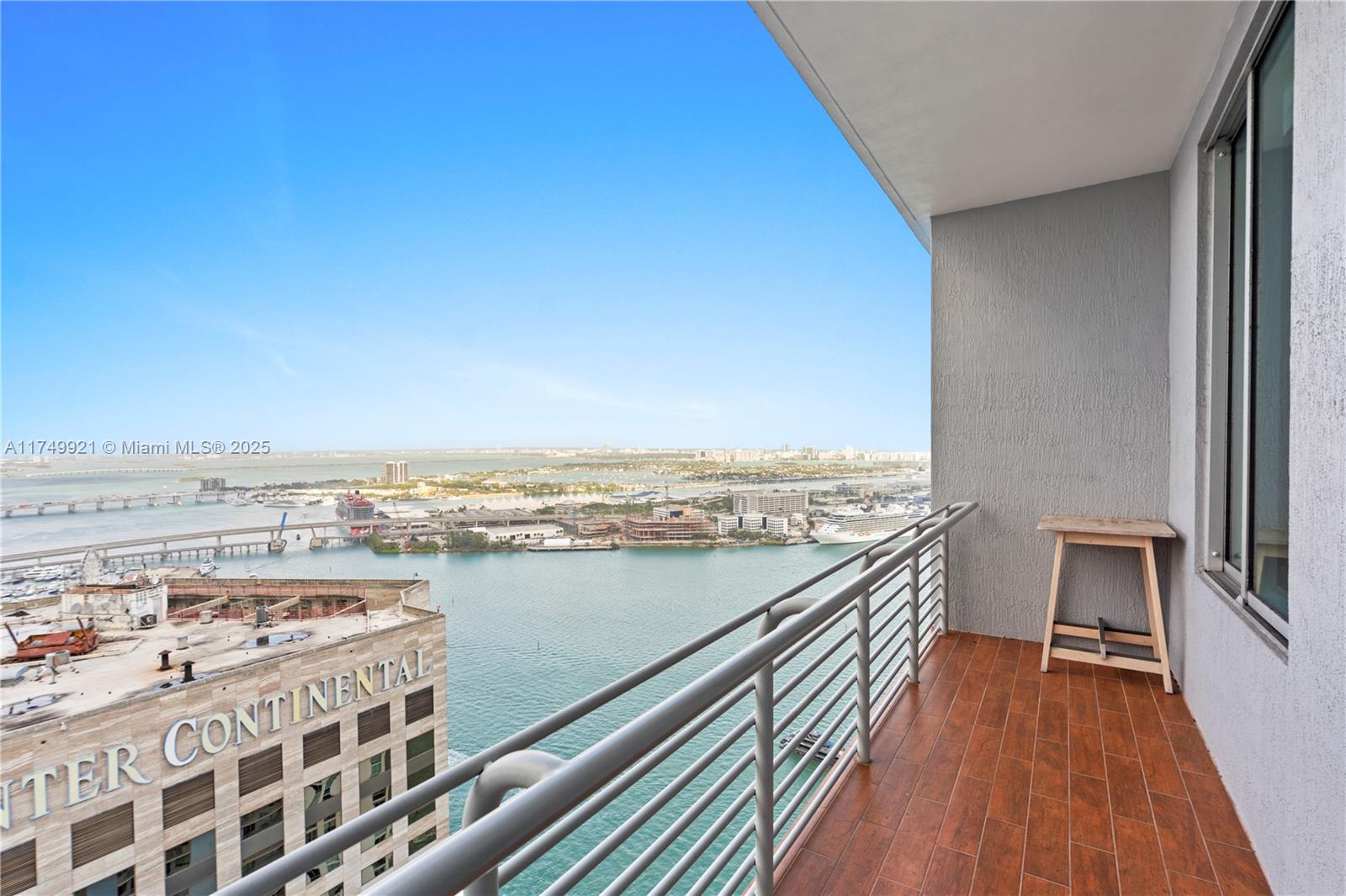 A balcony with wood-look tile flooring overlooks a harbor and city skyline — 335 S Biscayne Blvd, Miami FL 33131, MIAMI, FL