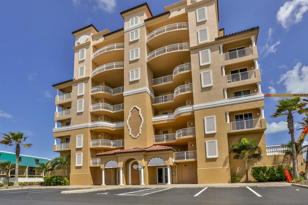 A multi-story tan stucco condominium building with balconies and a parking lot in the foreground — 711 S ATLANTIC AVENUE UNIT 603, NEW SMYRNA BEACH, FL