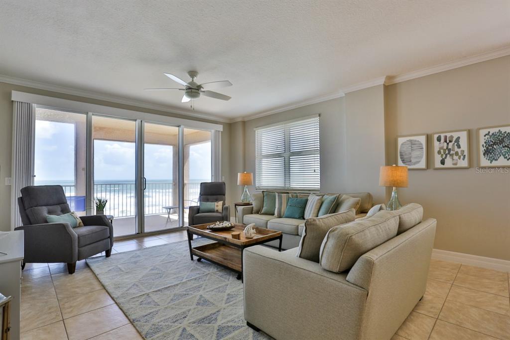A living room features a beige sofa, two armchairs, a coffee table, and ocean views — 711 S ATLANTIC AVENUE UNIT 603, NEW SMYRNA BEACH, FL