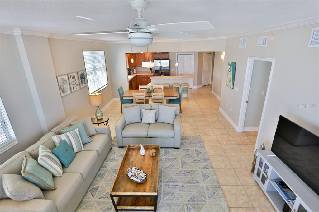 An open-concept living and dining area features tile flooring, a ceiling fan, and neutral furniture — 711 S ATLANTIC AVENUE UNIT 603, NEW SMYRNA BEACH, FL