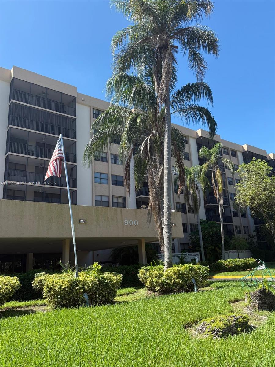 A multi-story apartment building with screened balconies and a palm tree in the foreground — 900 NE 195th St # 702, Miami FL 33179, MIAMI, FL