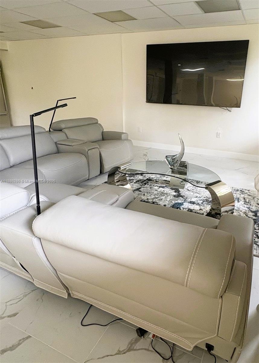 A living room features a light-colored leather sectional, a glass coffee table, and a wall-mounted television — 900 NE 195th St # 702, Miami FL 33179, MIAMI, FL