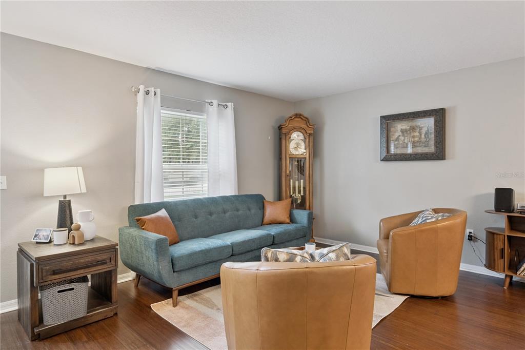 A living room features a blue sofa, two tan armchairs, and a grandfather clock — 2333 FOXTREE ROAD, TAVARES, FL
