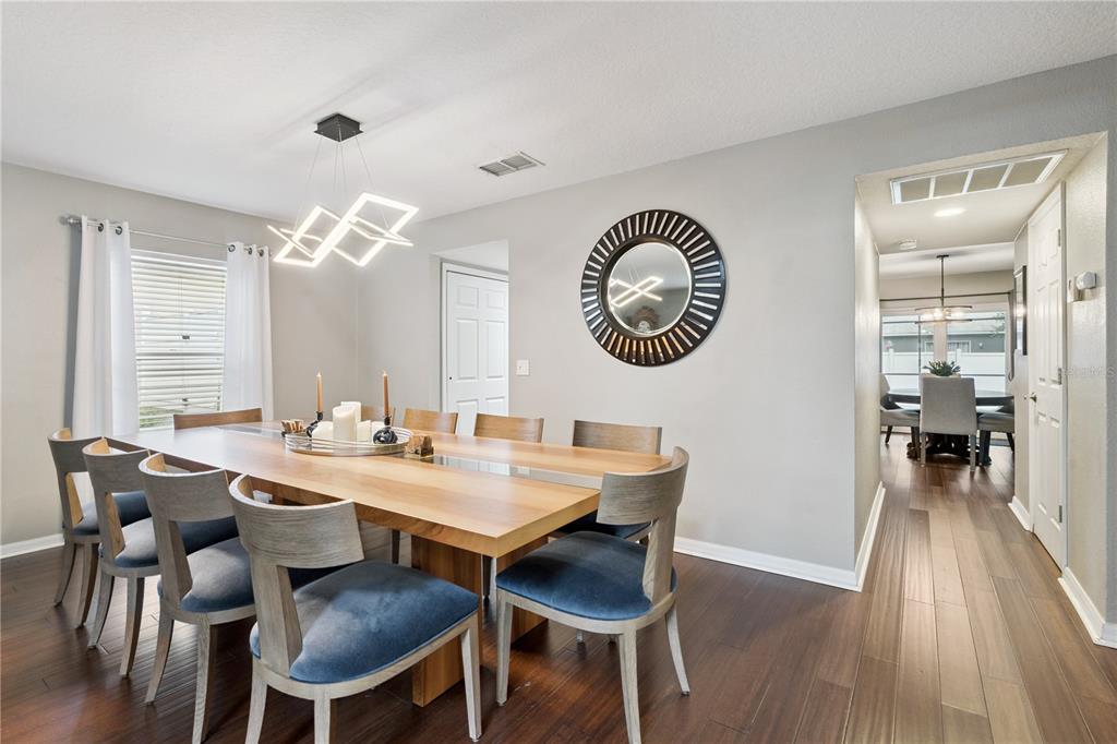 A dining room features a wooden table with blue chairs under a modern light fixture — 2333 FOXTREE ROAD, TAVARES, FL