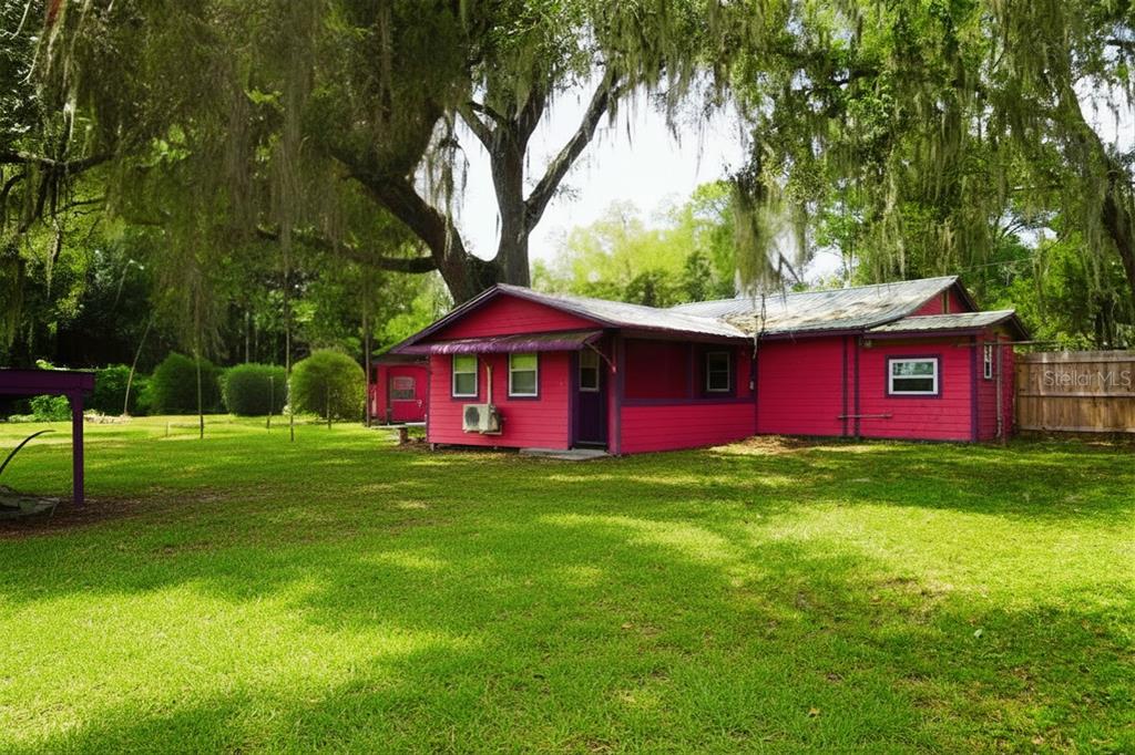 A bright pink house with a metal roof sits on a large, grassy lot — 11717 E SALMON DRIVE, FLORAL CITY, FL