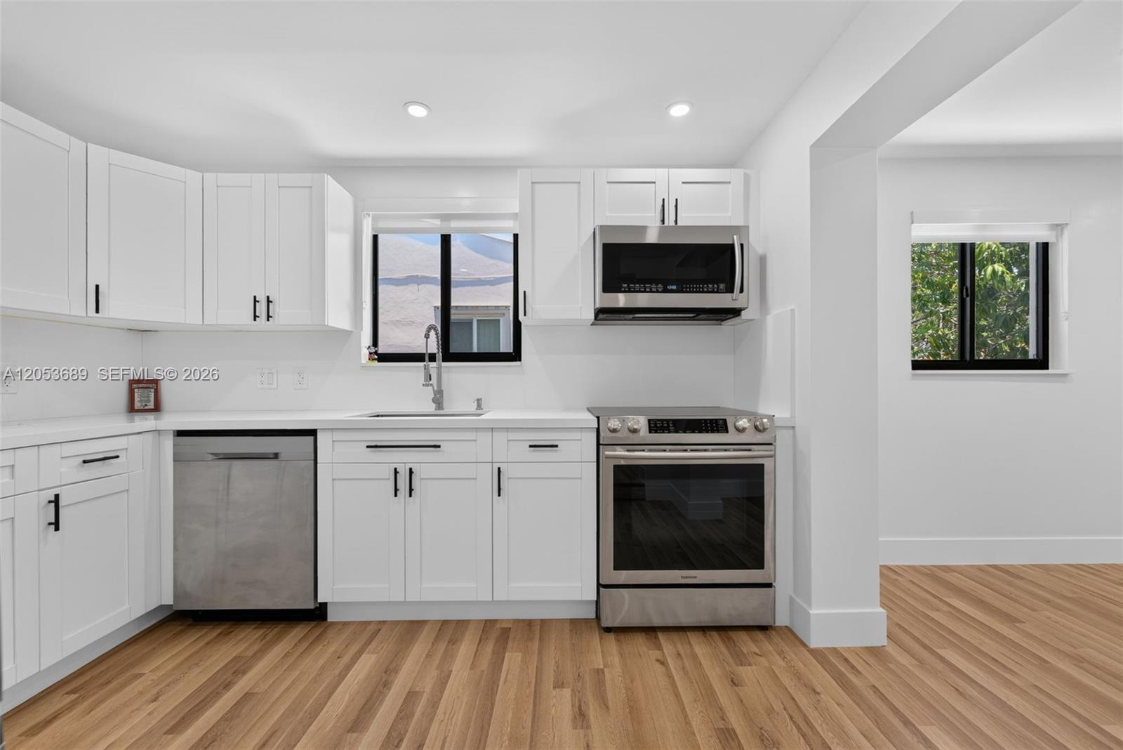A kitchen features white cabinets, stainless steel appliances, and light wood-look flooring — 1861 SW 22nd Ter, Miami FL 33145, MIAMI, FL