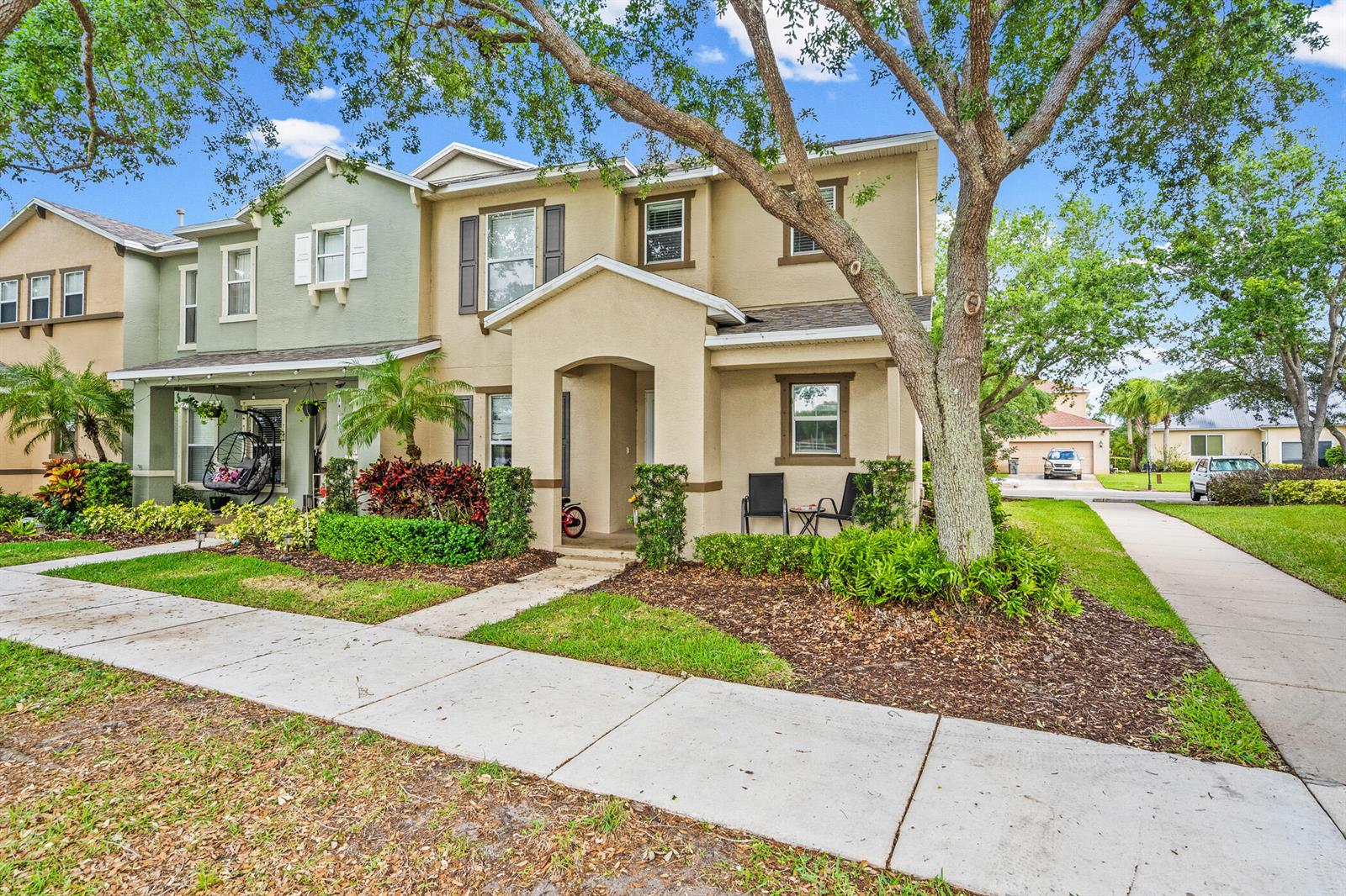 A two-story tan and green townhouse with a front porch, landscaping, and a large tree — 1814 Pointe West Way, Vero Beach FL 32966, VERO BEACH, FL