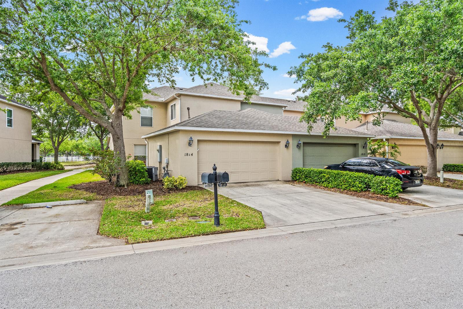 A two-story townhouse with a tan stucco exterior, a two-car garage, and a driveway — 1814 Pointe West Way, Vero Beach FL 32966, VERO BEACH, FL