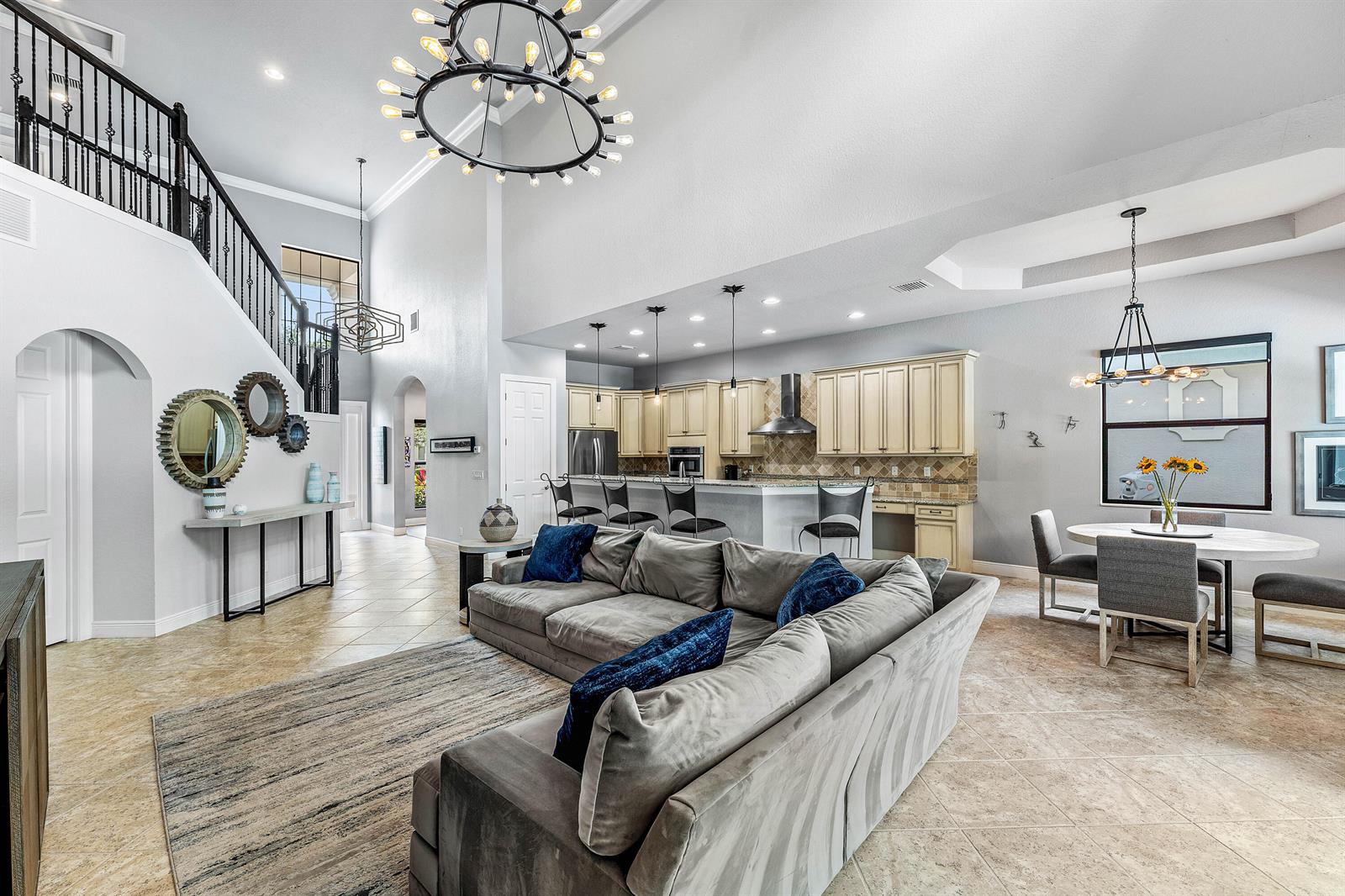 An open-concept living room and kitchen feature tile floors, a large sectional, and high ceilings — 10175 Cameilla Street, Parkland FL 33076, PARKLAND, FL
