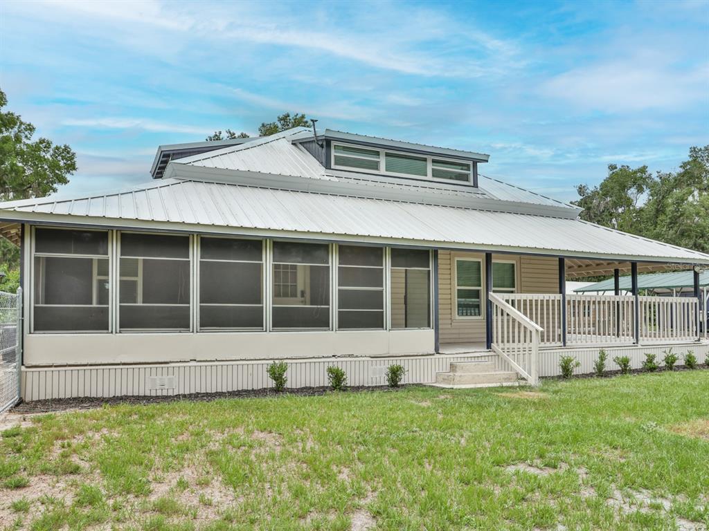 A house exterior featuring a metal roof, a screened-in porch, and a wooden deck — 3016 N MARYLAND AVENUE, PLANT CITY, FL