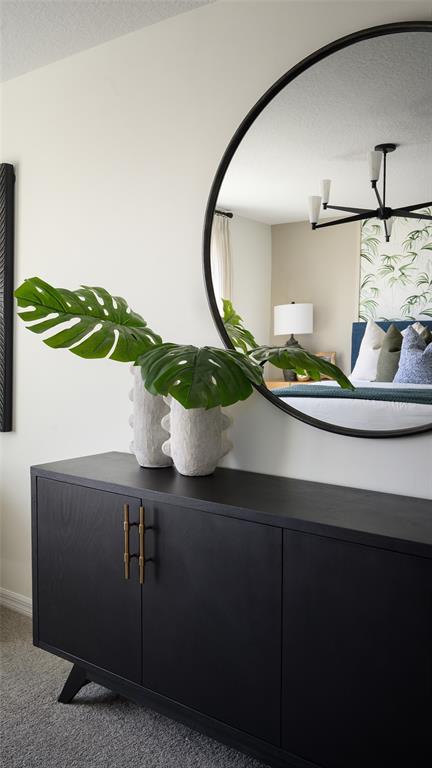 A black sideboard with two textured vases sits below a large round wall mirror — 34626 SILENT PINE RUN, DADE CITY, FL