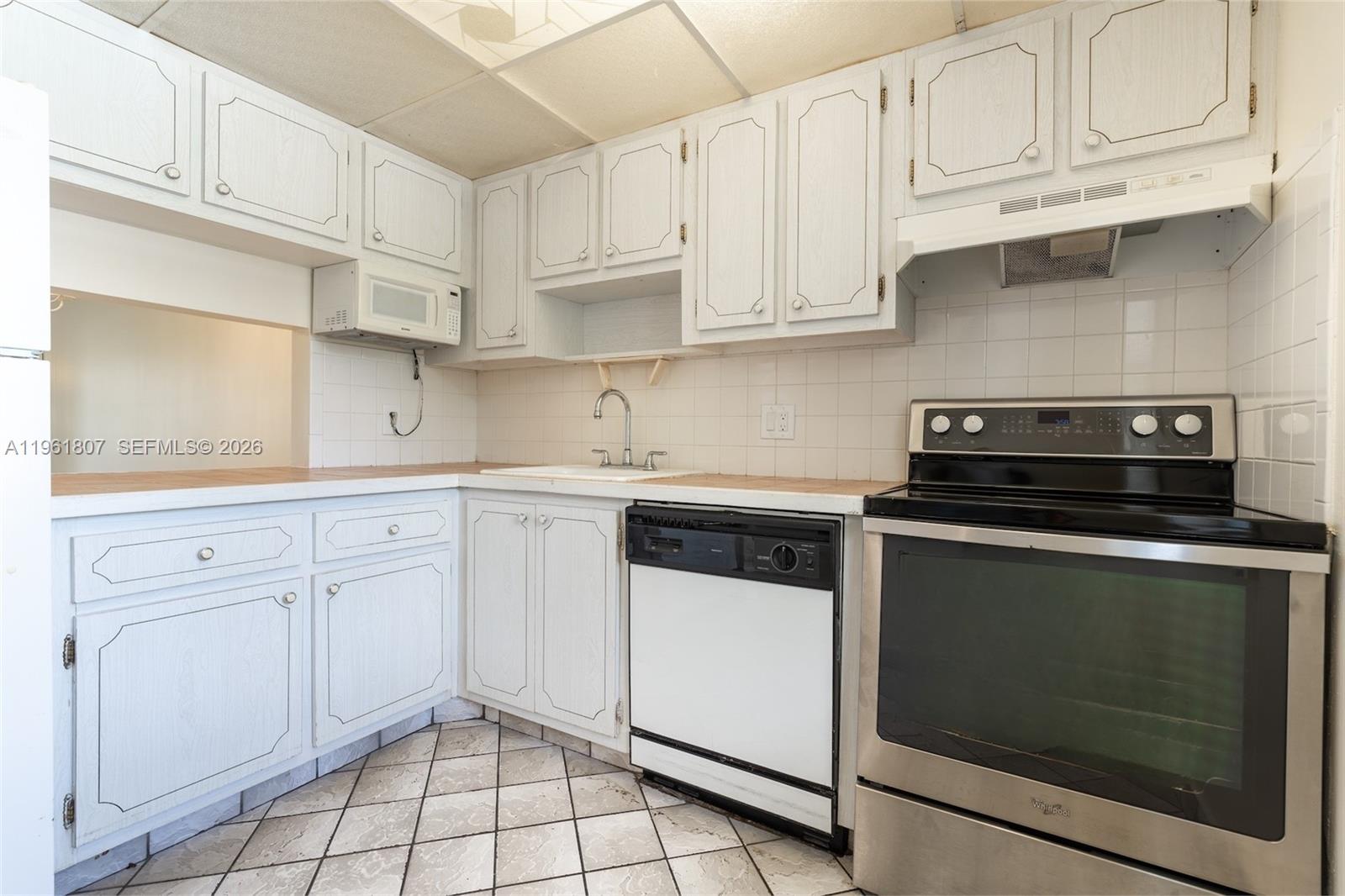 A kitchen features white cabinets, a stainless steel oven, a dishwasher, and tiled flooring — 7877 Golf Cir Dr # 108, Margate FL 33063, MARGATE, FL