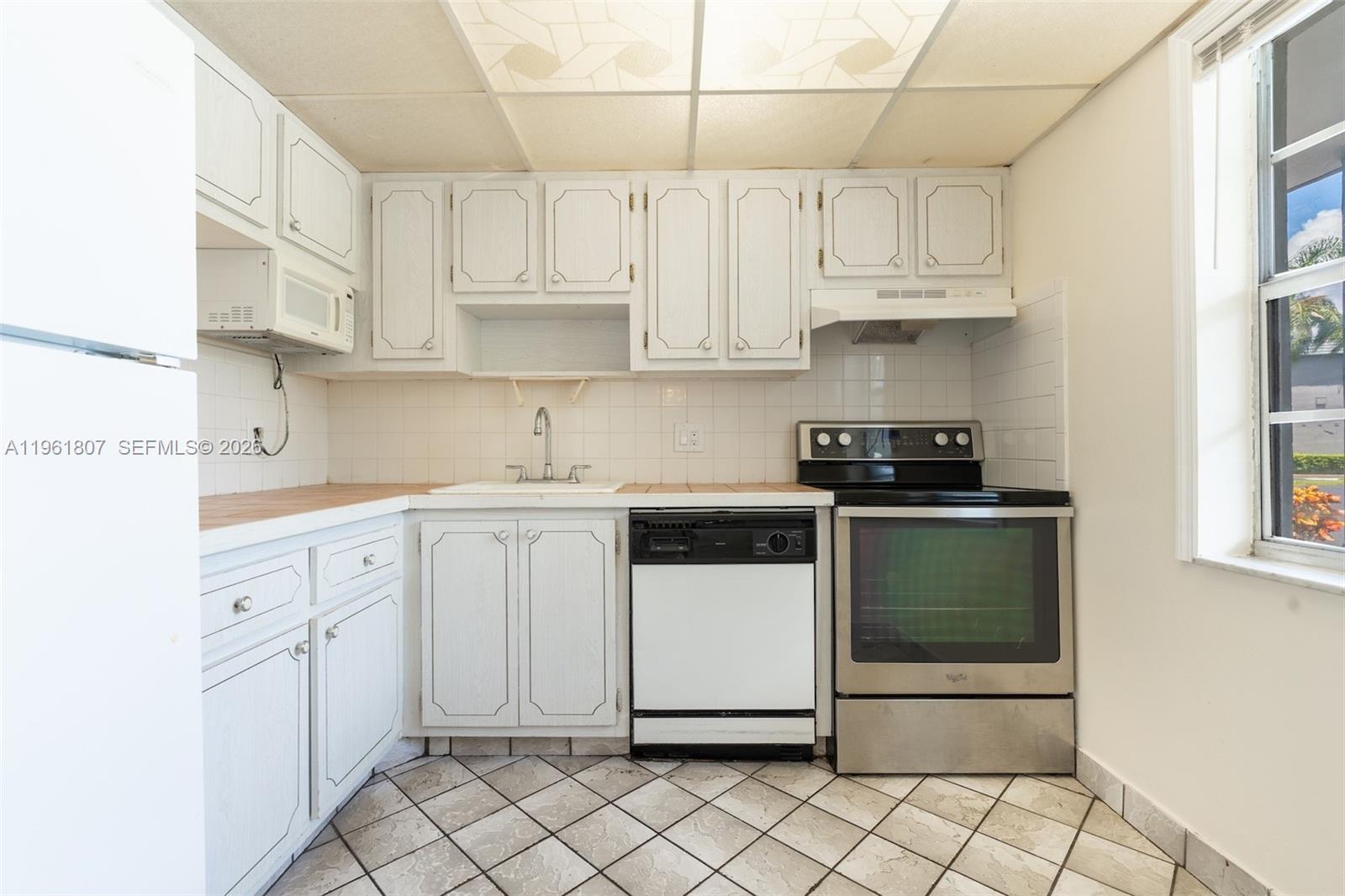 A kitchen features white cabinets, a stainless steel stove, a dishwasher, and tiled flooring — 7877 Golf Cir Dr # 108, Margate FL 33063, MARGATE, FL