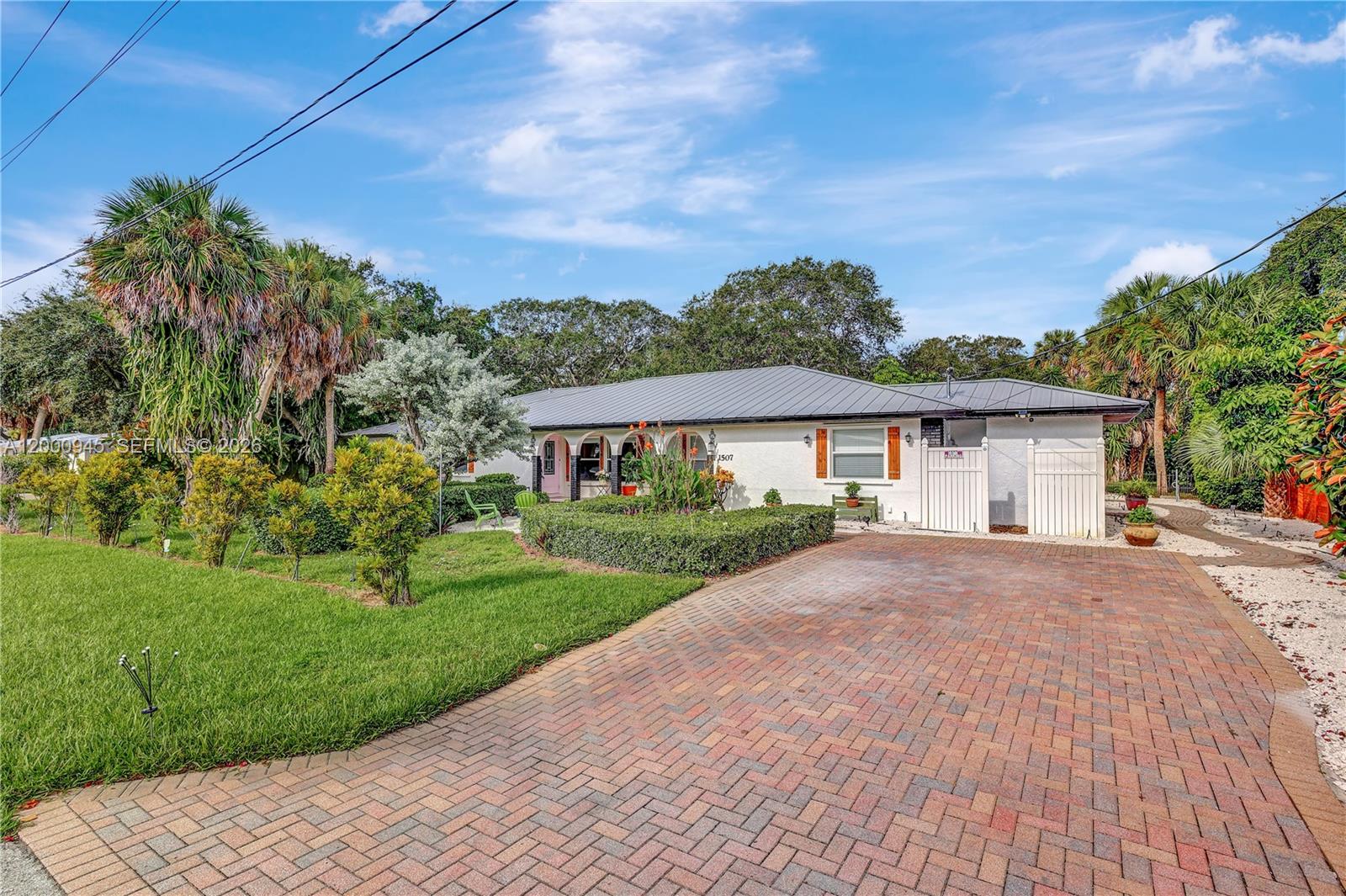 A single-story white house with a metal roof and a brick driveway — 1505 Coral Ave, Vero Beach FL 32963, VERO BEACH, FL