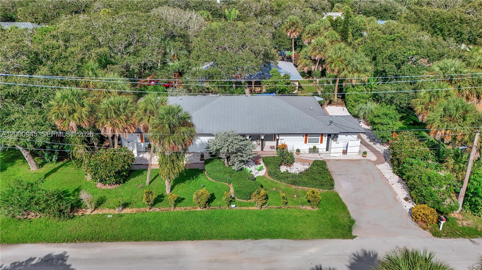 An aerial view shows a single-story house with a metal roof and a paved driveway — 1505 Coral Ave, Vero Beach FL 32963, VERO BEACH, FL