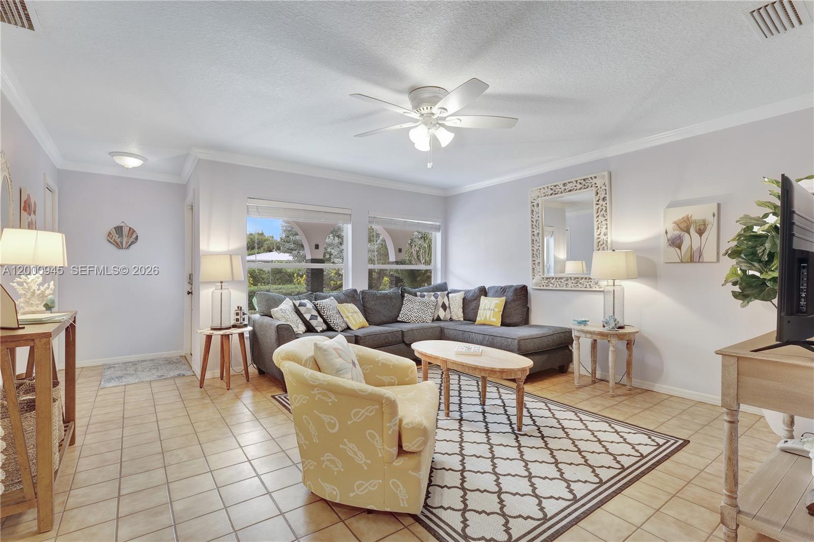 A living room features a gray sectional sofa, a yellow armchair, and tile flooring — 1505 Coral Ave, Vero Beach FL 32963, VERO BEACH, FL