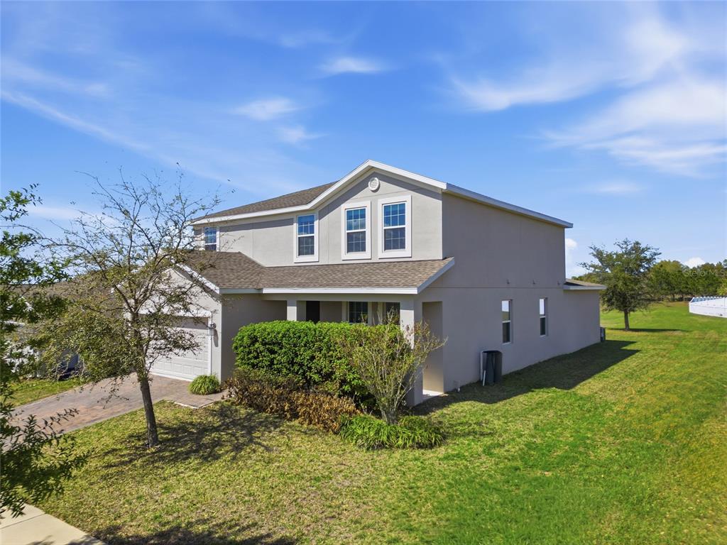 A two-story suburban house with a beige stucco exterior, a garage, and a grassy yard — 13 WHITE HORSE WAY, GROVELAND, FL