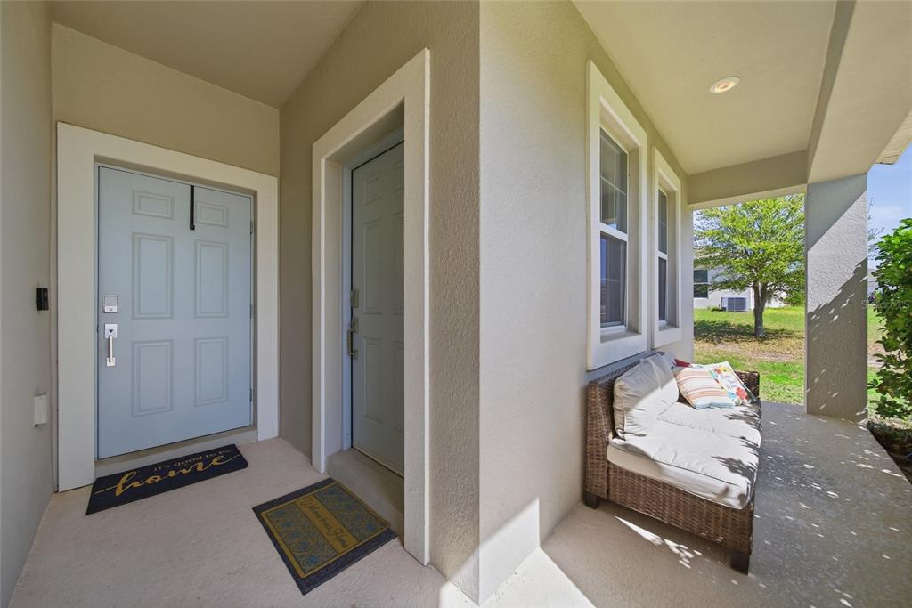 A covered porch features two light blue doors, a wicker sofa, and two welcome mats — 13 WHITE HORSE WAY, GROVELAND, FL