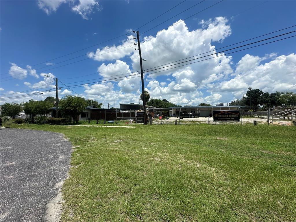 A fenced commercial lot features a single-story building and a Hutchinson Roofing sign — 1701 W MEMORIAL BOULEVARD, LAKELAND, FL