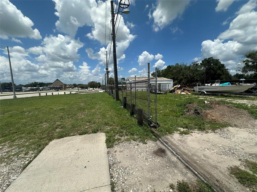 An outdoor view of a grassy lot with a chain-link fence and a boat — 1701 W MEMORIAL BOULEVARD, LAKELAND, FL