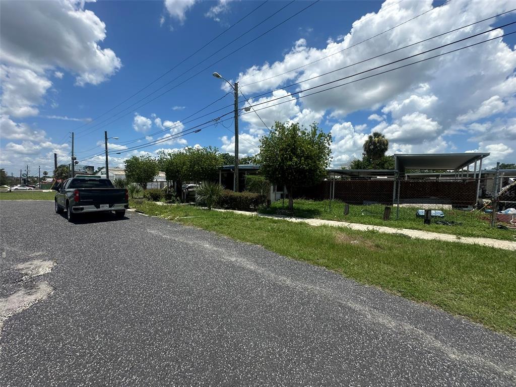 A street view of a residential property with a parked truck and a chain-link fence — 1701 W MEMORIAL BOULEVARD, LAKELAND, FL