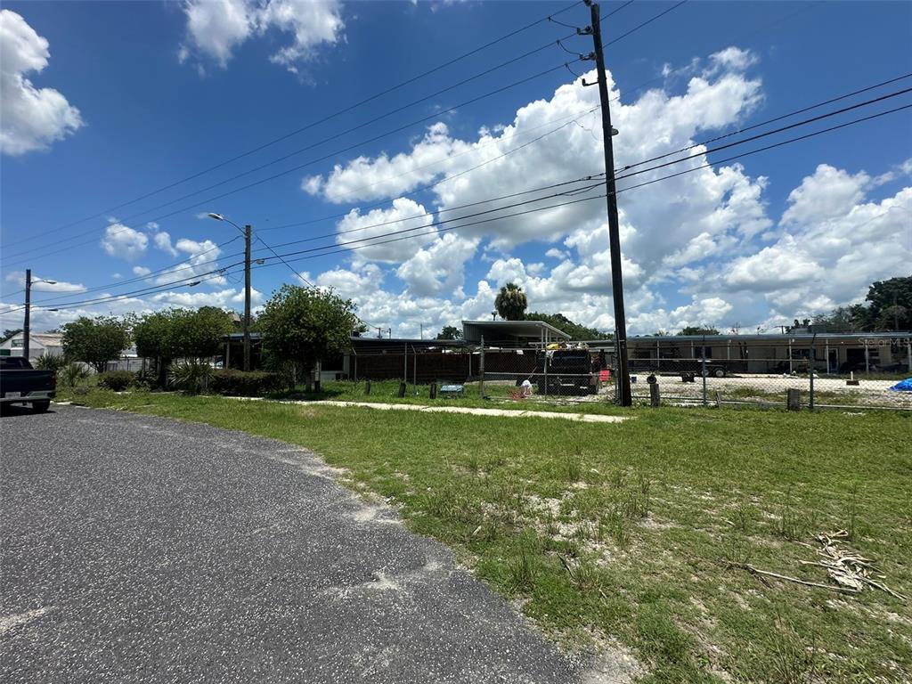 A fenced lot with a small structure and utility poles under a cloudy blue sky — 1701 W MEMORIAL BOULEVARD, LAKELAND, FL