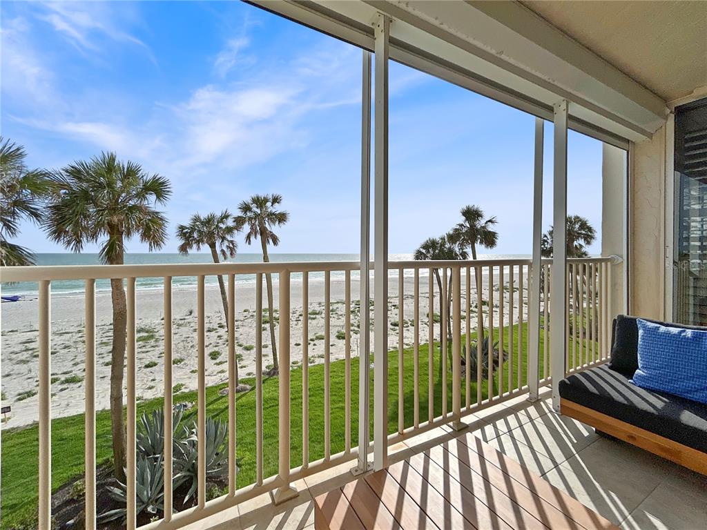 A balcony with a railing overlooks a sandy beach, palm trees, and the ocean — 4325 GULF OF MEXICO DRIVE UNIT 305, LONGBOAT KEY, FL