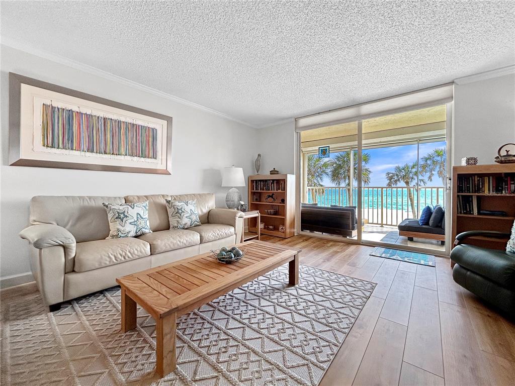 A living room features a beige sofa, wooden coffee table, and sliding doors overlooking the ocean — 4325 GULF OF MEXICO DRIVE UNIT 305, LONGBOAT KEY, FL