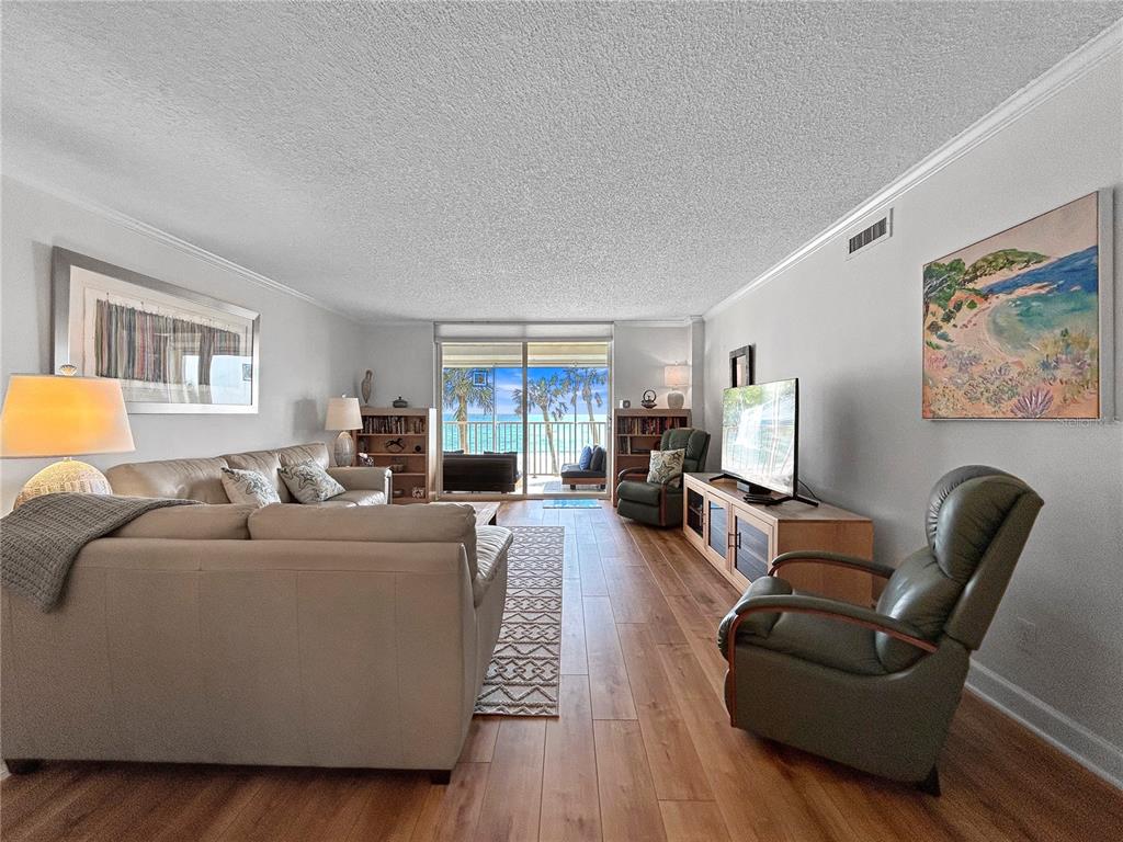 A living room with light wood floors, a beige sofa, and a view of the ocean — 4325 GULF OF MEXICO DRIVE UNIT 305, LONGBOAT KEY, FL
