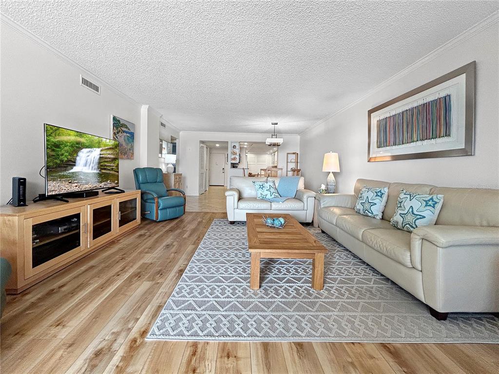 A living room features light wood flooring, a beige sofa, and a television on a console — 4325 GULF OF MEXICO DRIVE UNIT 305, LONGBOAT KEY, FL